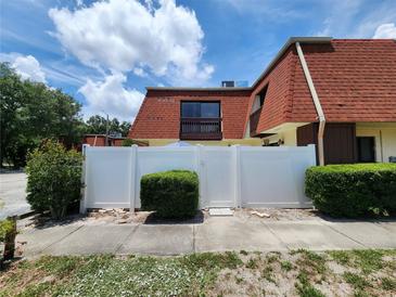 Two-story home with white privacy fence, red tile roof, and green landscaping at 8114 Oak Trace Way # C, Tampa, FL 33634