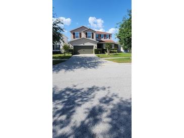 Charming two-story home features a manicured lawn, two-car garage, and warm curb appeal at 7620 Tangle Rush Dr, Gibsonton, FL 33534