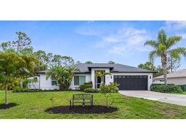 Charming renovated single-story home with a well-manicured lawn, mature landscaping, and a two-car garage at 2421 Valkaria Ave, North Port, FL 34286
