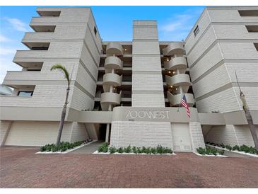 Contemporary condo building featuring private balconies, well-kept landscaping, and a view of the parking area at 19700 Gulf Blvd # 204, Indian Shores, FL 33785