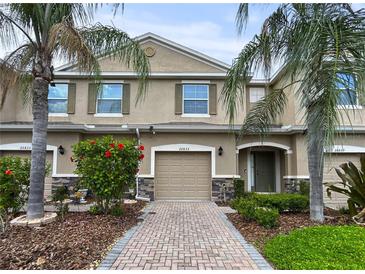 Inviting townhome with a well manicured front yard, brick driveway, and lush tropical landscaping at 26835 Juniper Bay Dr, Wesley Chapel, FL 33544