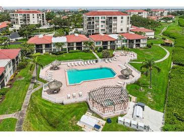 Aerial view of the community pool, complete with tiki huts, lounge chairs, and manicured landscaping at 6218 Palma Del Mar S Blvd # 103, St Petersburg, FL 33715