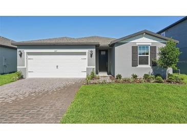 Charming single-Gathering home features a well-manicured lawn and a brick paved driveway at 1817 Draughton Dr, Zephyrhills, FL 33541
