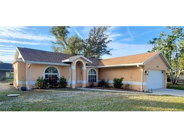 Charming single-story home with arched windows, beautiful landscaping, and a well-maintained lawn at 1835 Rival Ter, North Port, FL 34286