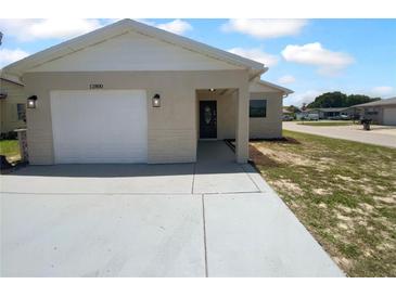 Charming single-story home featuring an attached garage, covered entry and a well-maintained lawn at 12800 Kellywood Cir, Hudson, FL 34669