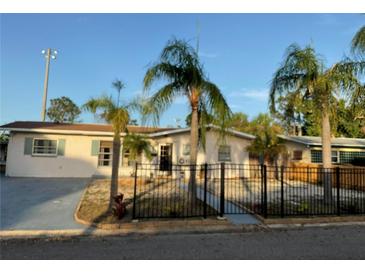 Inviting single-story home with palm trees, a black fence, and a well-maintained lawn at 3680 Whiting Se Dr, St Petersburg, FL 33705