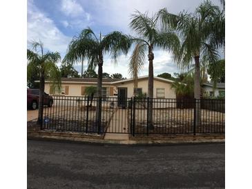 Charming single-story home with mature palm trees and a fenced front yard at 3680 Whiting Se Dr, St Petersburg, FL 33705