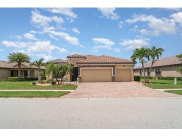 Beautiful home featuring a tile roof, three-car garage, and a well-manicured lawn with palm trees at 20323 Granlago Dr, Venice, FL 34293