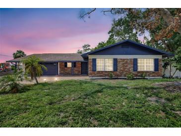 Charming single-story brick home featuring a well-kept lawn and a cozy, inviting front facade at dusk at 8701 Thornwood Ln, Tampa, FL 33615