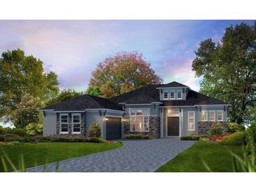 New construction gray home featuring stone accents, professional landscaping, and a paver driveway at 5008 Sea Branch Ave, Apollo Beach, FL 33572