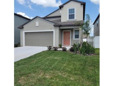 Two-story home featuring a landscaped yard, a gray garage door, and a charming peach-colored front door at 13707 Newbridge St, Spring Hill, FL 34609