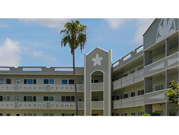 The condominium building features a well-kept exterior, a tropical palm tree, and a light gray color scheme at 2257 World Parkway W Blvd # 61, Clearwater, FL 33763