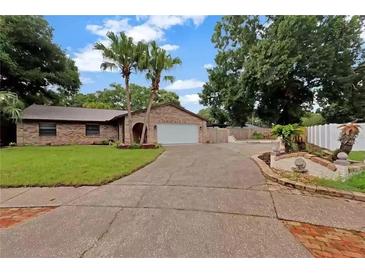 Charming brick home featuring a well-maintained lawn, mature trees, and a two-car garage at 15609 Timberline Dr, Tampa, FL 33624