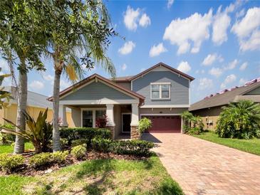 Charming two-story home with a well-maintained yard and a brick-paved driveway under a bright blue sky at 19491 Paddock View Dr, Tampa, FL 33647