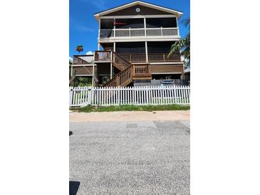 Charming multi-level home featuring multiple decks, brown siding, and a quaint white picket fence at 19105 Whispering Pines Dr, Indian Shores, FL 33785