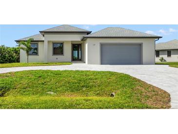 A charming single-story home boasts a gray roof, manicured lawn, and a paved driveway leading to an attached garage at 27 Bunker Ct, Rotonda West, FL 33947