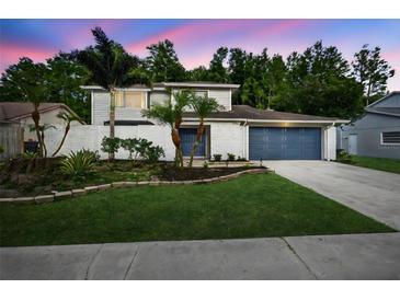 Charming two-story home with blue garage door and landscaped front yard with trees and white brick accents at 4404 Grainary Ave, Tampa, FL 33624