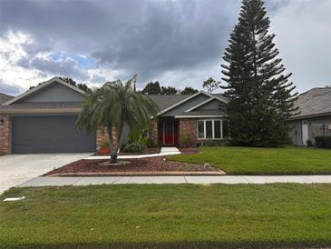 Charming single-Gathering home featuring a red door, well-manicured lawn, and mature trees under a cloudy sky at 1403 Ventana Dr, Sun City Center, FL 33573