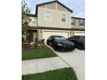 Inviting two-story townhouse with attached garage, landscaped yard, and well-manicured lawn at 10302 Lavender Aster Trl, San Antonio, FL 33576