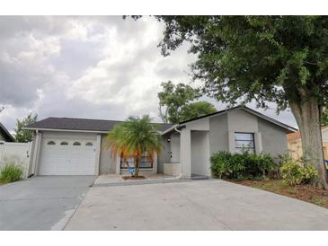 Charming single-story home featuring a gray exterior, well-maintained lawn, mature landscaping, and a two car garage at 9516 Woodborough Ct, Tampa, FL 33615