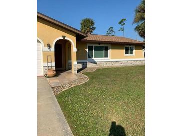 Single-story home with a well-maintained lawn, neutral paint, and welcoming arched entryway at 1409 Yorkshire St, Port Charlotte, FL 33952