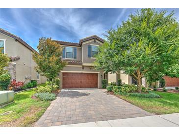 Charming two-story home featuring a brick driveway and a well-manicured front yard with mature trees at 12990 Burns Dr, Odessa, FL 33556