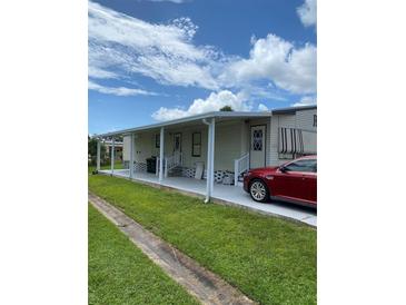 Mobile home with covered patio and carport,red car parked nearby at 6480 Center Lane, North Port, FL 34287