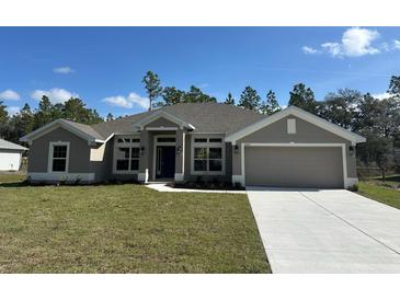 Charming single-story home featuring a well-manicured lawn, neutral color palette, and an attached two-car garage at 12283 Ipswich Sparrow Rd, Weeki Wachee, FL 34614