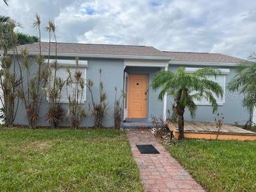 Single story home with orange door and brick walkway at 431 80Th Way, St Pete Beach, FL 33706