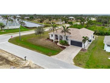 Beautiful home with a paver driveway, lush lawn and decorative palm trees at 8305 Welsford Rd, Port Charlotte, FL 33981