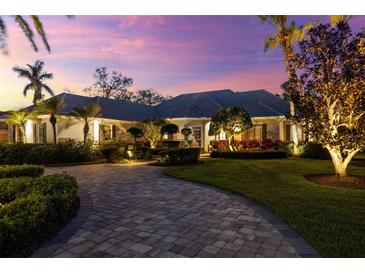 Charming home featuring manicured landscaping, a brick driveway, and elegant outdoor lighting at twilight at 2546 Tom Morris Dr, Sarasota, FL 34240