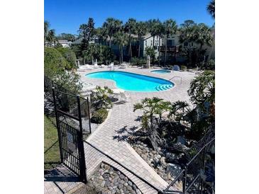 Inviting community pool area with lounge chairs surrounded by lush landscaping on a sunny day at 4939 Marina Palms Dr, Port Richey, FL 34668