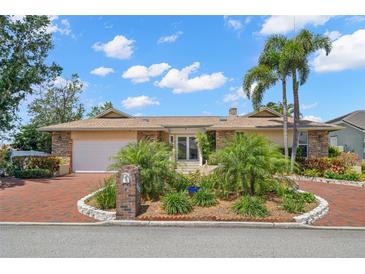 Inviting home featuring a brick driveway, lush landscaping, and beautiful curb appeal, complete with palm trees at 852 3Rd Ave S, Tierra Verde, FL 33715