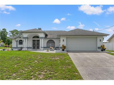 Charming single-story home featuring white exterior, gray accents, well-maintained lawn, and an attached two-car garage at 5188 Elwood Rd, Spring Hill, FL 34608