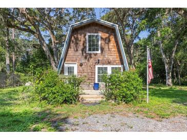 Quaint A-frame home with wood siding and a small front porch surrounded by lush greenery at 8309 Oakgren Rd, Brooksville, FL 34601