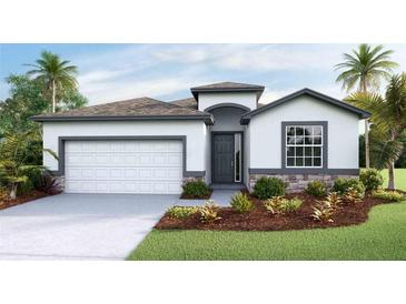Inviting single-story home with a stone-accented facade, two-car garage, and beautifully landscaped front yard at 11332 Curio Dr, Brooksville, FL 34613