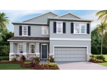 Two-story home featuring stone accents, gray siding, dark shutters, and a two-car garage at 11352 Curio Dr, Brooksville, FL 34613