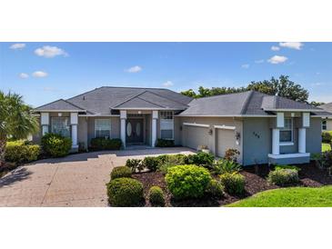 Charming single-story home featuring manicured landscaping, a gray roof, and a brick driveway with a two-car garage at 305 Lake Tahoe Ct, Englewood, FL 34223