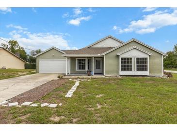 Charming single-story home with green siding, a well-manicured lawn, and an attached two-car garage at 14150 Prospect St, Spring Hill, FL 34609