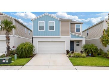 Charming two-story home with a two-car garage, neatly landscaped yard and blue and tan accent colors at 5528 Summer Sunset Dr, Apollo Beach, FL 33572