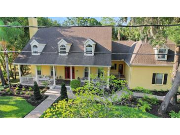 Charming two-story yellow house with landscaped yard and brick walkway at 8608 Poinsettia Dr, Temple Terrace, FL 33637