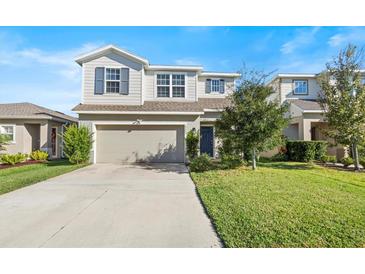 Two-story house with a neutral color scheme, a two-car garage, and a well-manicured lawn at 10662 Hawks Landing Dr, Land O Lakes, FL 34638