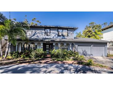 Two-story house with gray siding, landscaped yard, and a two-car garage at 4911 W Juno St, Tampa, FL 33629