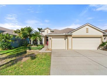 House exterior features a three-car garage and landscaped yard at 1820 Mira Lago Cir, Ruskin, FL 33570