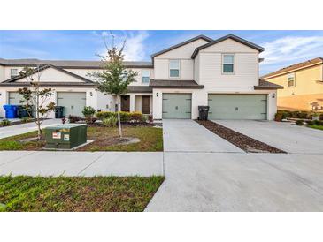 Modern townhomes featuring well-maintained lawns and two-car garages, plus stylish landscaping, and neutral color schemes at 5327 New Friendship Pl, Tampa, FL 33619