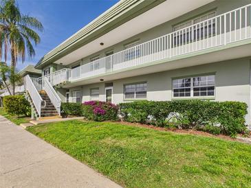 Two-story condo building featuring white railings, stairs, and lush green landscaping at 1433 S Belcher Rd # G13, Clearwater, FL 33764
