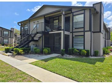 Two-story condo with an exterior staircase, screened in patio, and landscaping at 14663 Norwood Oaks Dr # 103, Tampa, FL 33613