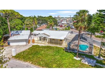Charming home boasts a metal roof, inviting front porch, and screened-in pool, perfect for relaxation at 3620 E Tampa Cir, Tampa, FL 33629