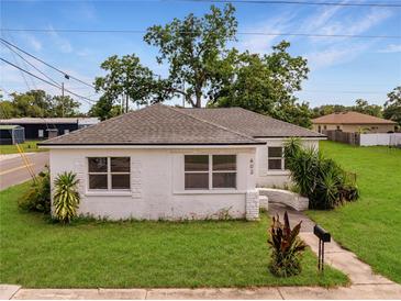 Charming white home with a well-manicured lawn and mature trees under a beautiful blue sky at 602 E Laura St, Plant City, FL 33563