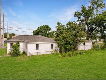 White exterior view of a charming home with green lawn and mature landscaping at 602 E Laura St, Plant City, FL 33563